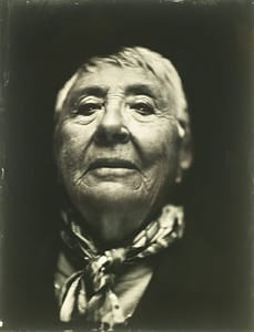 A black and white photo of an old woman with a scarf featured in Stories of the Dat Do Dogs.